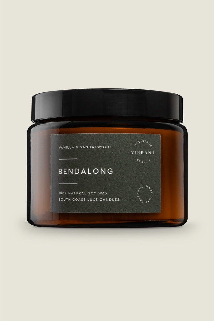 A brown glass jar with a black lid labeled 'Bendalong' containing a candle. The label has white and green text and a symbol.