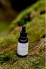 Bottle of Botanic Boost Hyaluronic Serum product on a mossy surface