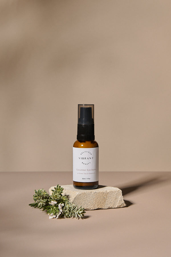 Cucumber Eye Balm bottle with a label on a beige background