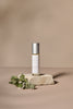 Headache Ease roller bottle with greenery on a beige background