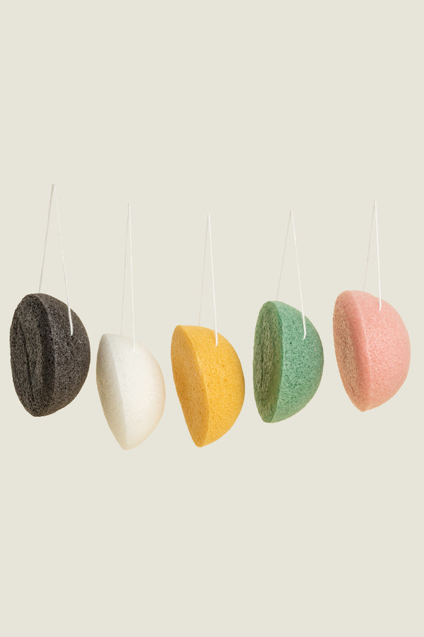 A selection of colorful Konjac facial sponges hanging by a string, displayed in a row.