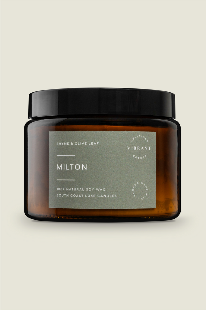 A large glass jar candle with a black lid, labeled 'Milton - Thyme and Olive Leaf'. The candle is made from soy wax and is scented with thyme and olive leaf oils.