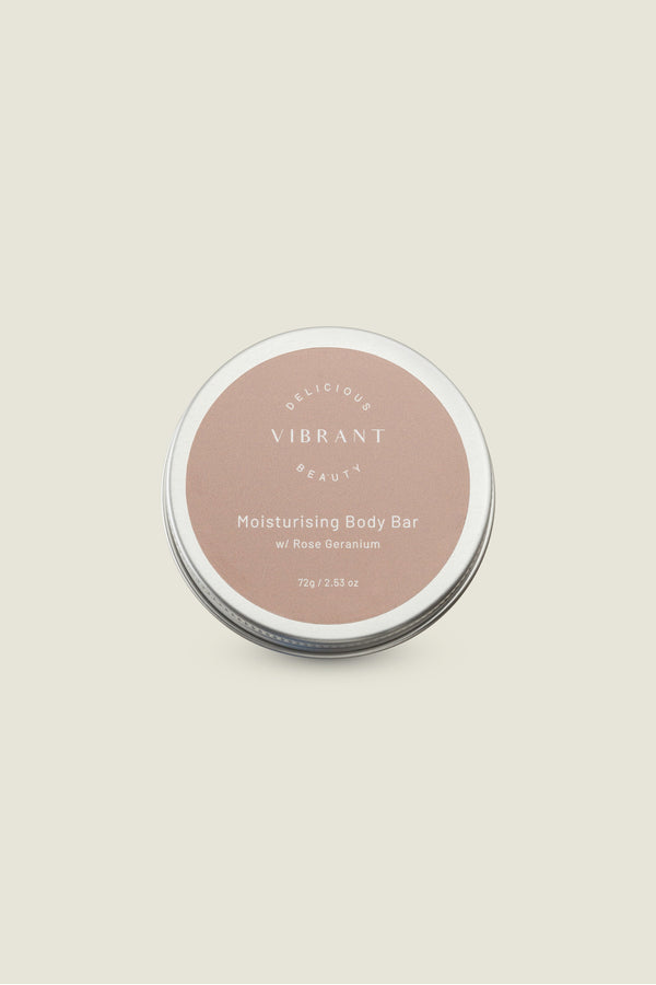 A solid moisturizing body bar in a tin container with a label on the lid. The label has text indicating that it is a moisturizing body bar with rose fragrance.