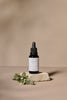Black glass dropper bottle with white label on a beige background