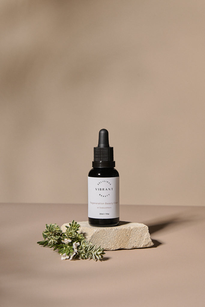 Black glass dropper bottle with white label on a beige background