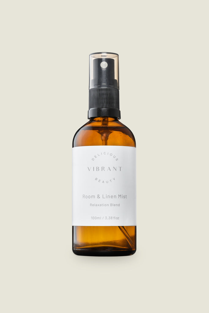 n amber glass bottle with a spray nozzle, labeled with 'Delicious Vibrant Beauty' and the product name 'Linen & Room Spray Relaxation Blend'.