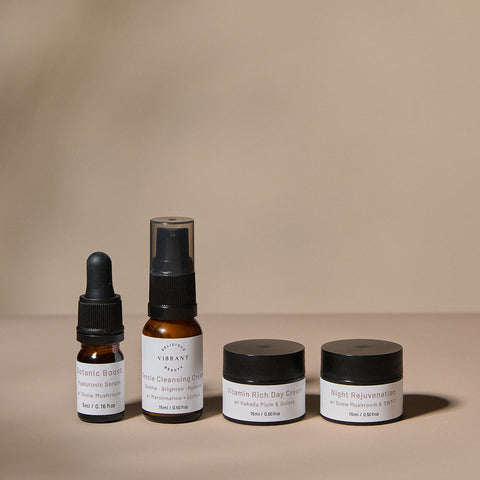 Set of Delicious Vibrant Beauty mini sized skincare products including bottles and jars on a beige background